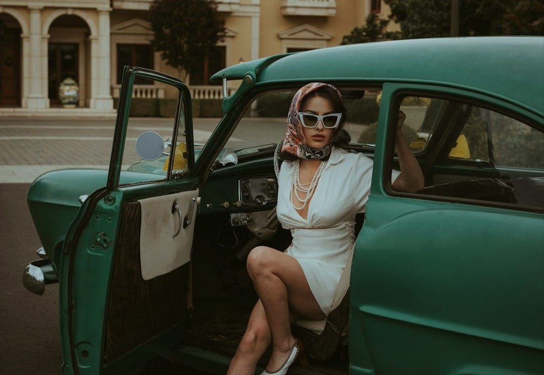 a woman sitting in the back of a green car