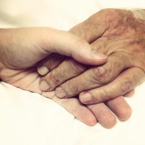 This may contain: an older person holding the hand of a younger person