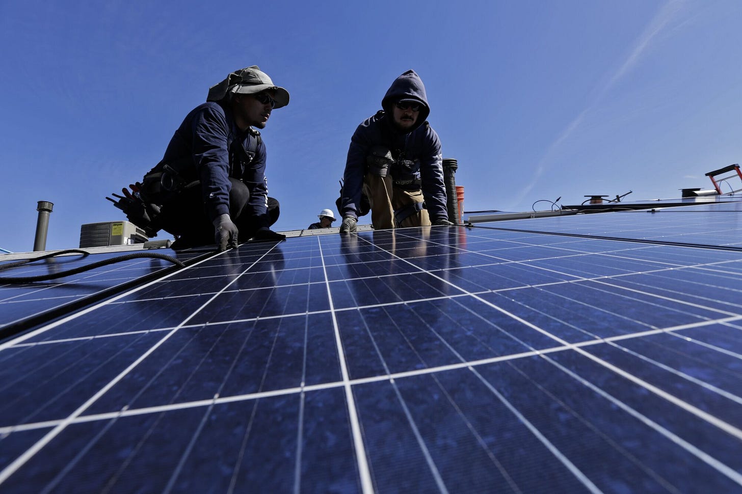 Two men install solar panels on a roof. Two men install solar panels on a roof.