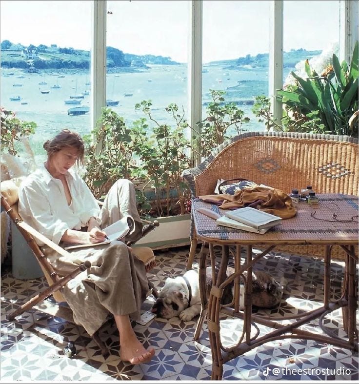 This may contain: a woman sitting in a wicker chair next to a table with a dog on it