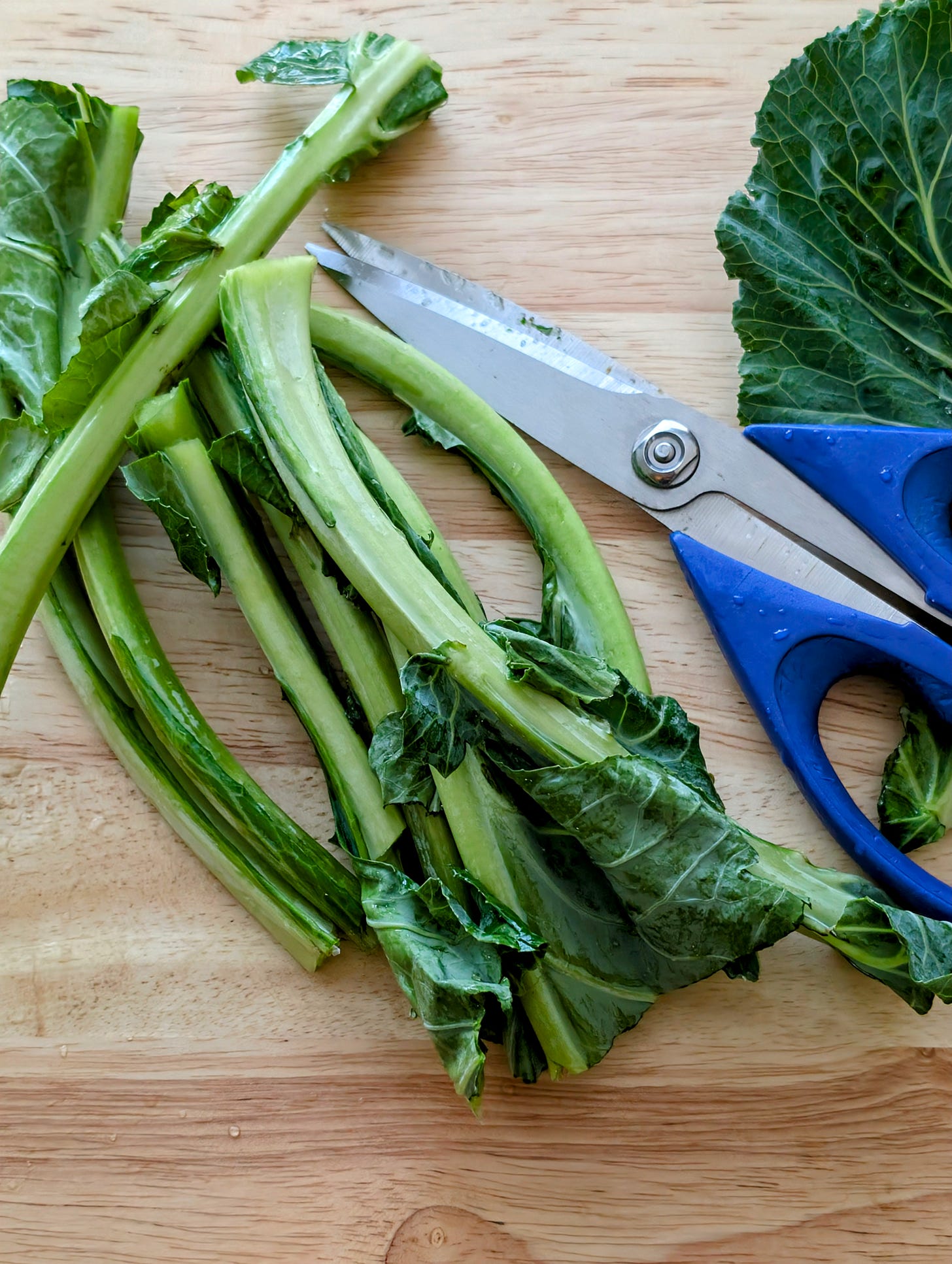 Collard green stems cut and set aside on a cutting board.