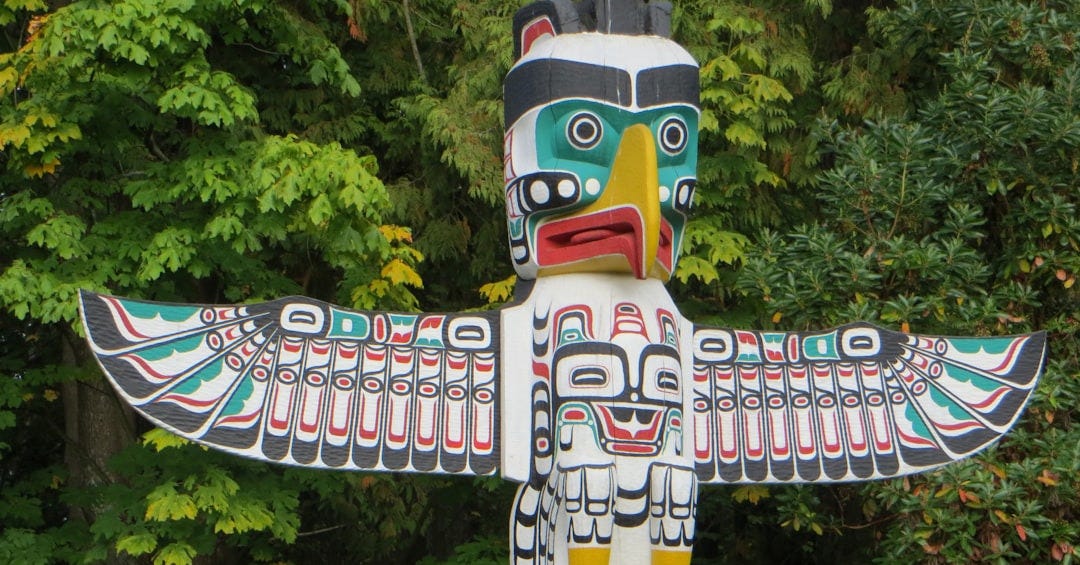 Intricately carved totem pole with bird and animal figures. Intricately carved totem pole with bird and animal figures.