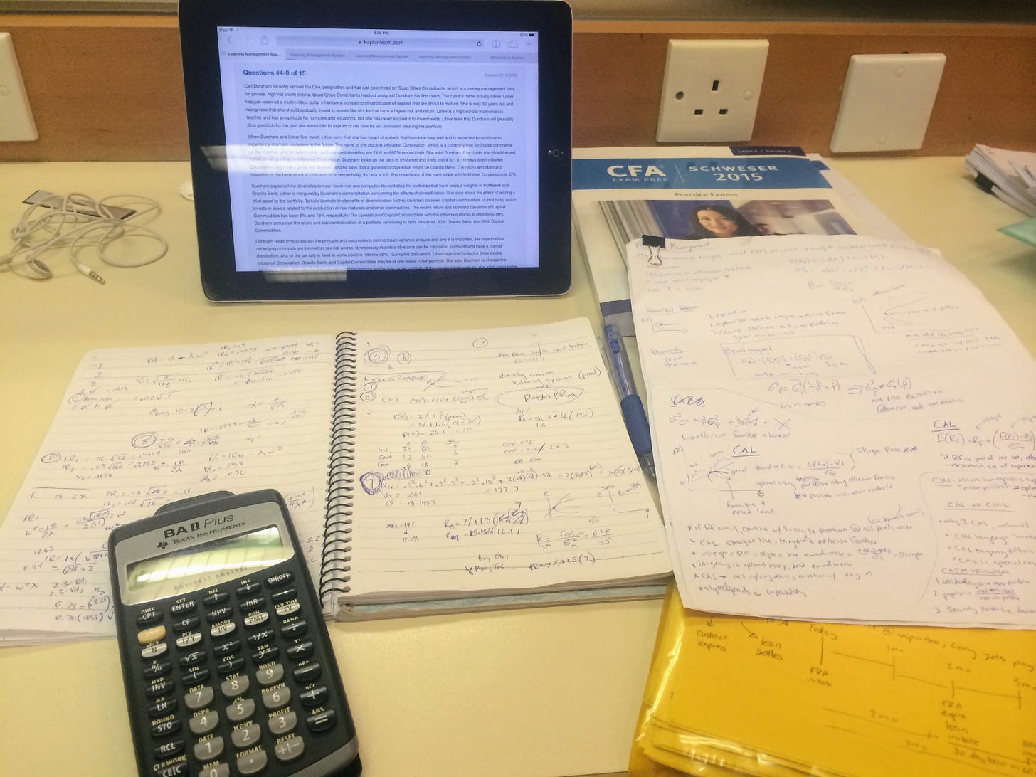 CFA exam study materials including textbooks, handwritten notes, and a financial calculator on a desk CFA exam study materials including textbooks, handwritten notes, and a financial calculator on a desk