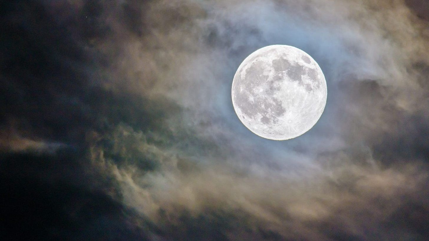 image: full moon surrounded by wispy clouds