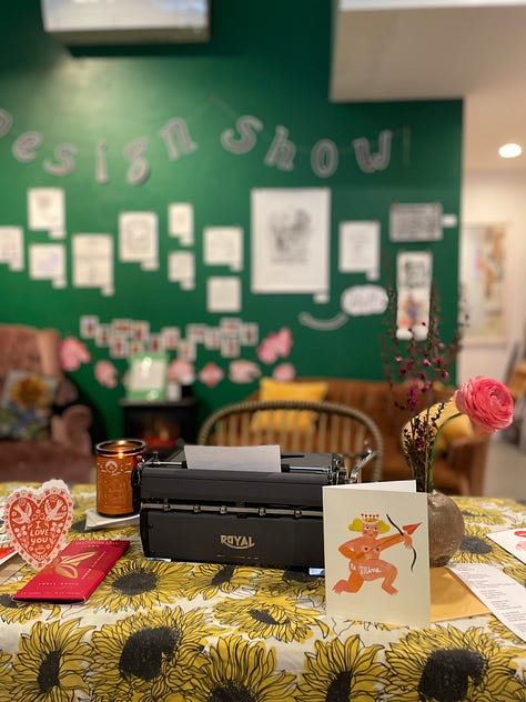 Typewriter set up on a card table in a bookshop and three index cards with haiku on them.