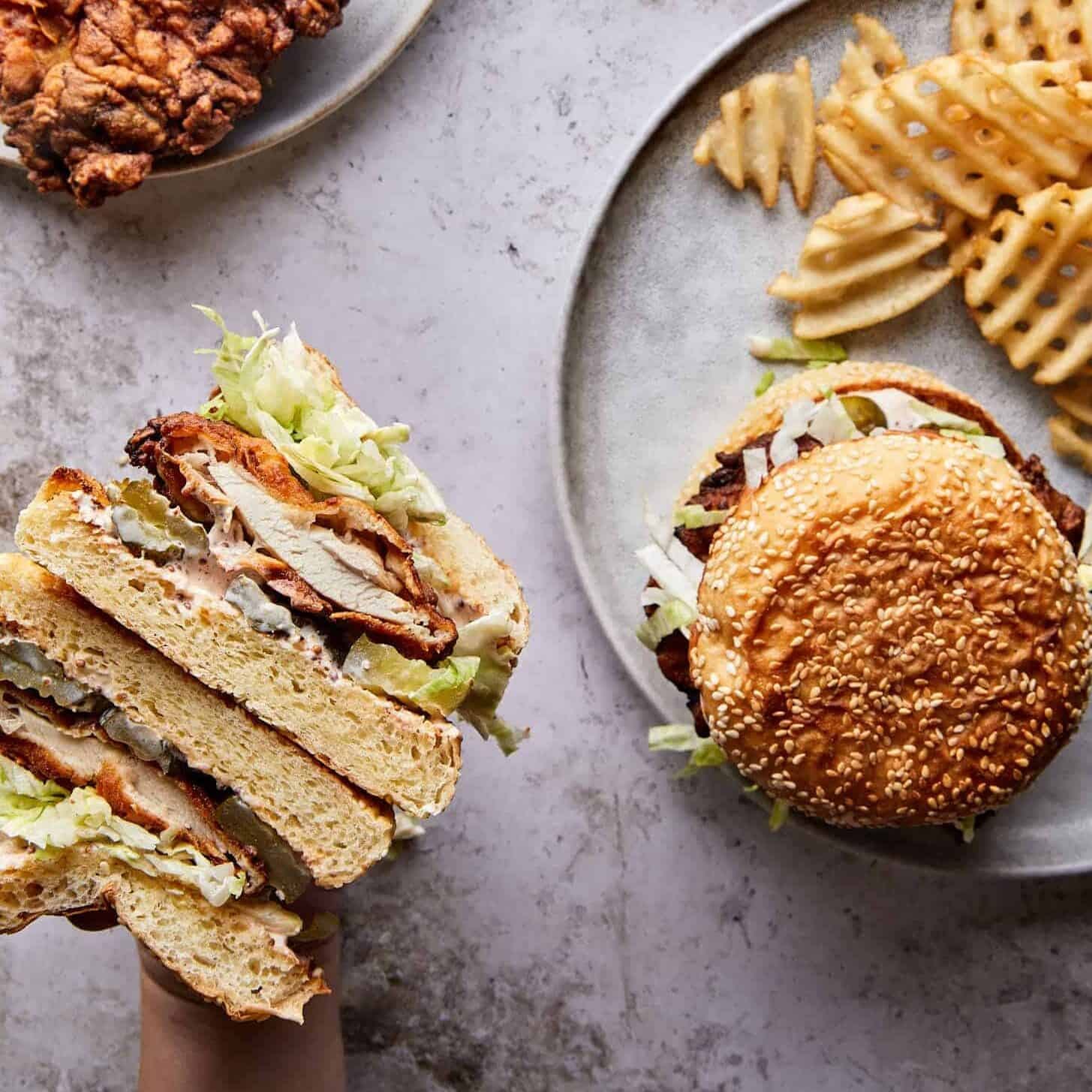 The best fried chicken sandwich recipe you'll ever try—golden, crispy chicken on a buttery brioche bun with tangy pickles, spicy oil, and a kick of something sweet being held over a plate of waffle fries.
The best fried chicken sandwich recipe you'll ever try—golden, crispy chicken on a buttery brioche bun with tangy pickles, spicy oil, and a kick of something sweet being held over a plate of waffle fries.