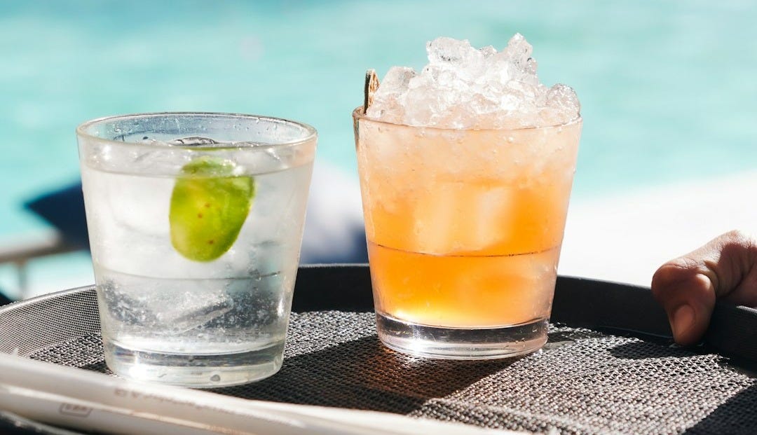 Two cocktails served on a tray by the pool.