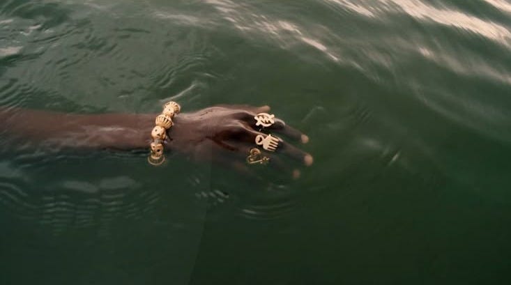 This may contain: a man swimming in the water with two gold bracelets on his hand