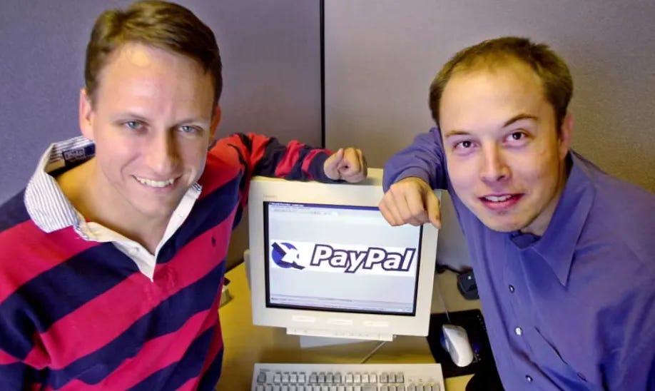 PayPal co-founders Peter Thiel and Elon Musk in 2000, posing with a computer displaying the original PayPal logo during the company’s early days.