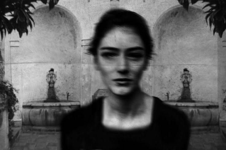 This may contain: a black and white photo of a woman in front of a fountain with statues behind her This may contain: a black and white photo of a woman in front of a fountain with statues behind her