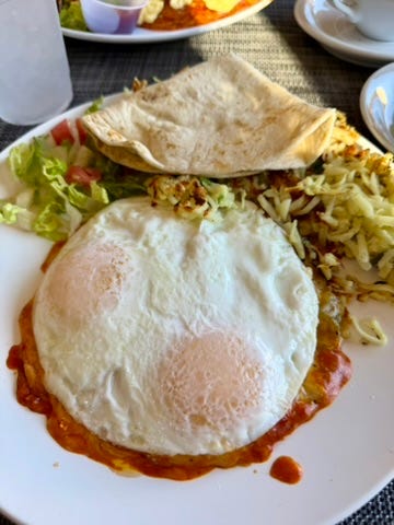 eggs over easy on top of red and green enchilada with a handmade tortilla on the side