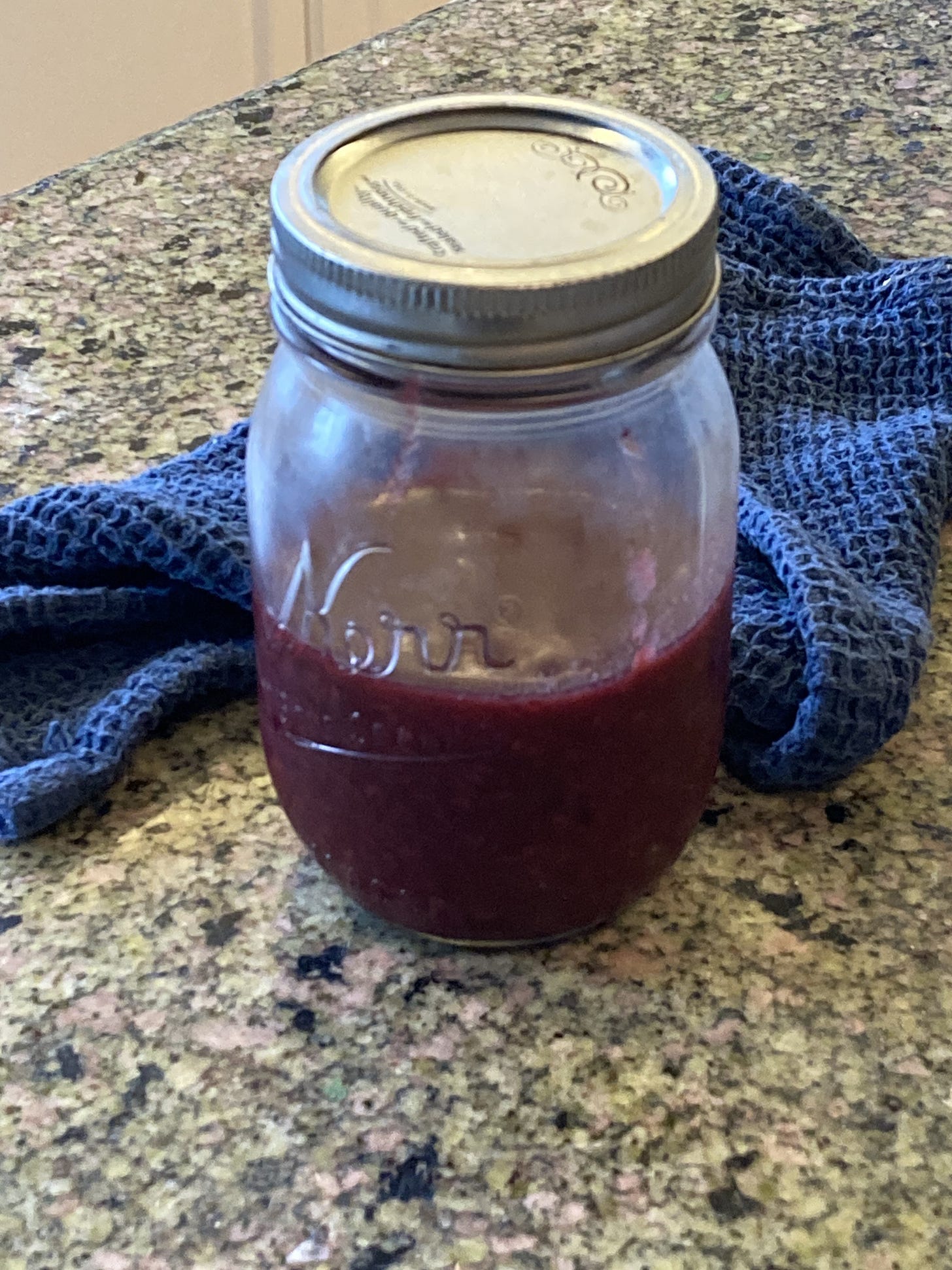 Deeply purple fruit compote in a mason jar with a blue towel Deeply purple fruit compote in a mason jar with a blue towel