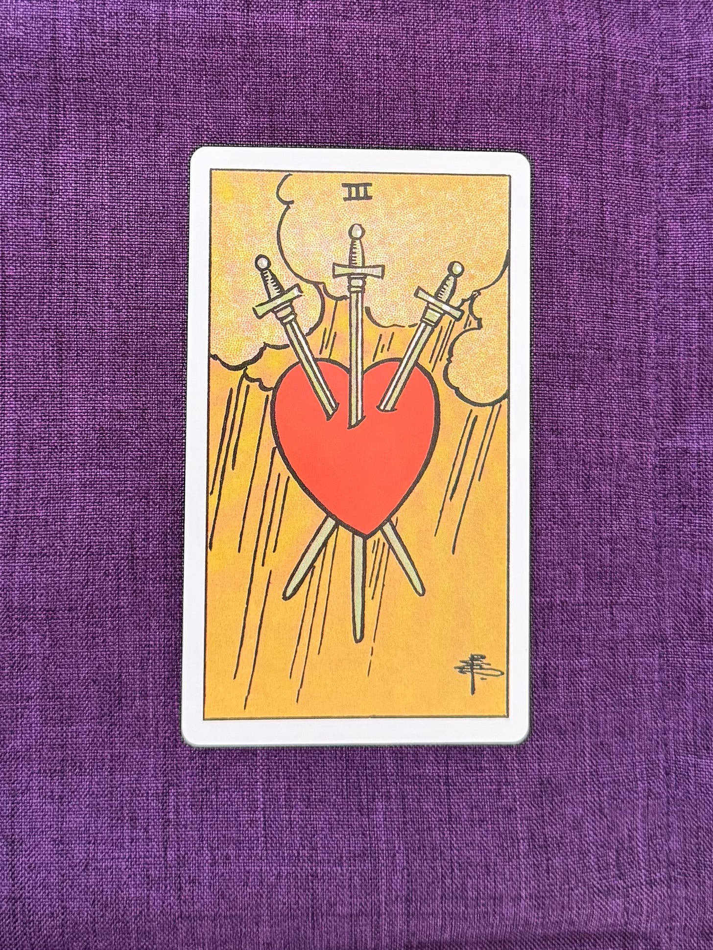 A gray sky filled with heavy clouds forms the background. At the center, a red heart is pierced by three long swords—one angled downward from above, and two crossing diagonally from either side. Rain falls in straight lines across the scene, surrounding the heart and blades.