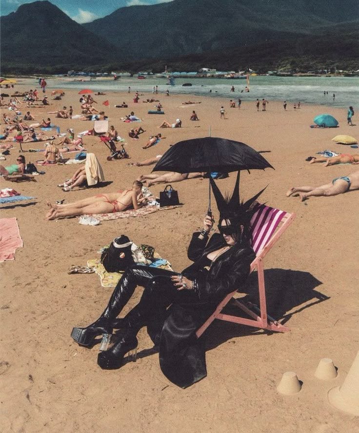 This may contain: two people sitting in lawn chairs on the beach with an umbrella over their heads,