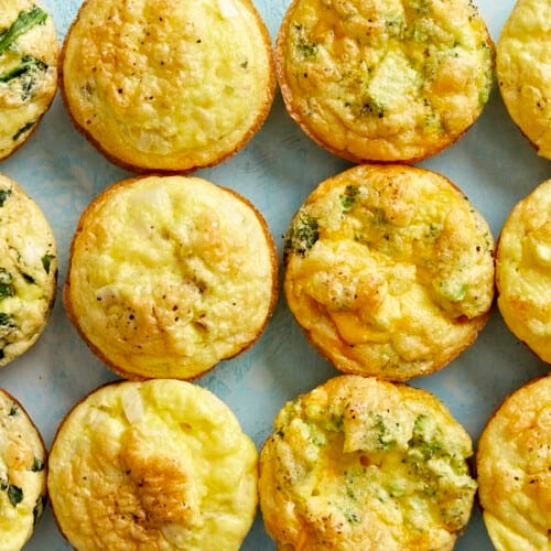Cooked egg muffins lined up in a grid on a blue surface.