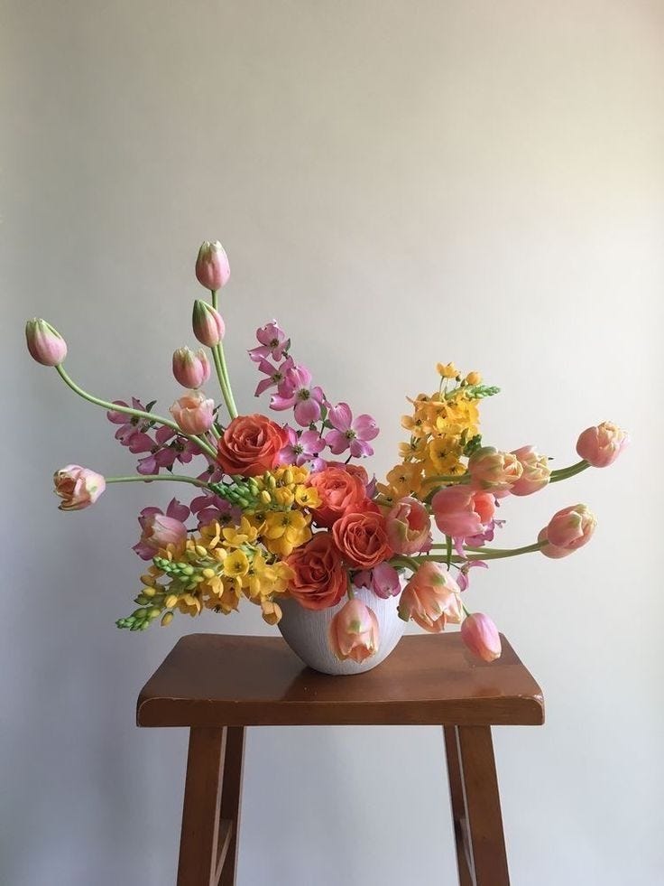 This may contain: a vase filled with flowers sitting on top of a wooden table