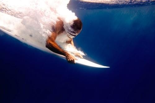 This may contain: a man riding a wave on top of a surfboard in the ocean under water