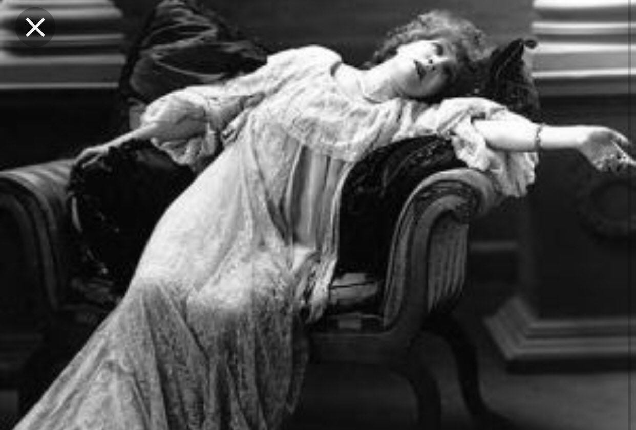 A black-and-white picture of a woman in an old-timey nightgown swooning dramatically on a large chair