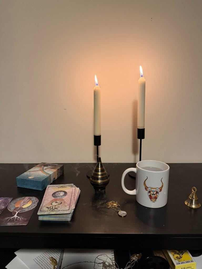 Photo of ancestral altar with candles, water in mug, and oracle cards. 