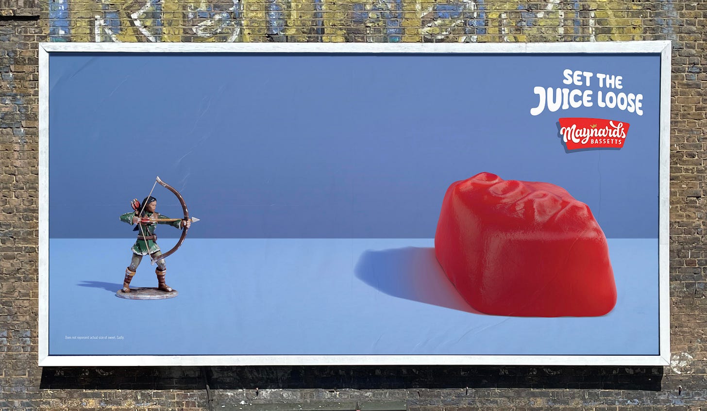 Poster showcasing a miniature model archer on the left looking like it will pierce the skin of a red port winegum on the right side of the poster. Logo for Maynards Bassetts with endline saying set the juice loose in top right corner. 
The concept is to leave the viewer to imagine that when the arrow pierces the skin of the sweet it would set the juice loose much like the explosion of flavour that happens in your mouth when eating Winegums.