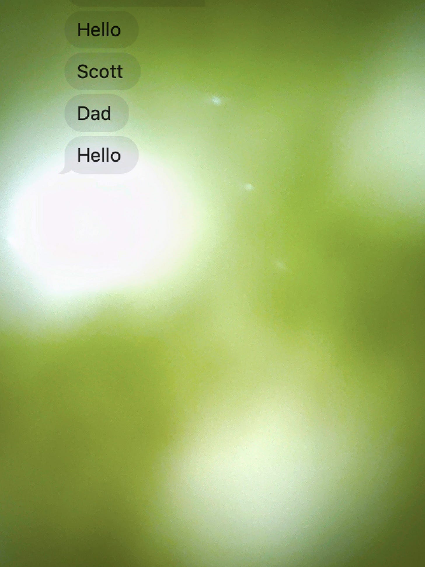 A blurred green background with text messages. The messages read, "Hello. Scott. Dad. Hello."