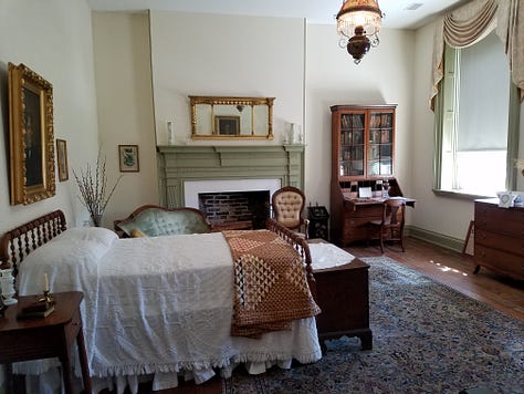 The Dickson Williams Mansion, a brick building with a white porch; the parlor, showing a round table surrounded by black chairs on a red oriental rug in front of a fireplace; the kitchen area, showing original north carolina furniture; bedrooms of the house, along with a portrait of General John Hunt Morgan sitting in a chair in a black coat with tall black boots; and the bed where he spent his last night.