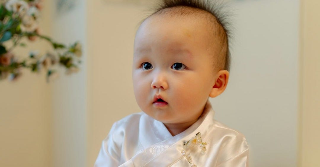 baby in white dress shirt sitting on bed