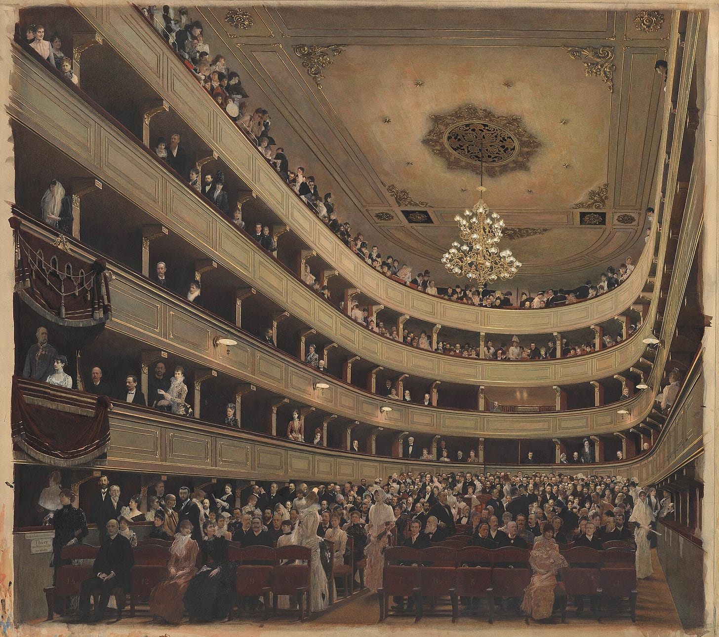A view from the stage into a horseshoe of tiered boxes packed with tiny figures in evening dress, a chandelier hanging from the ceiling.