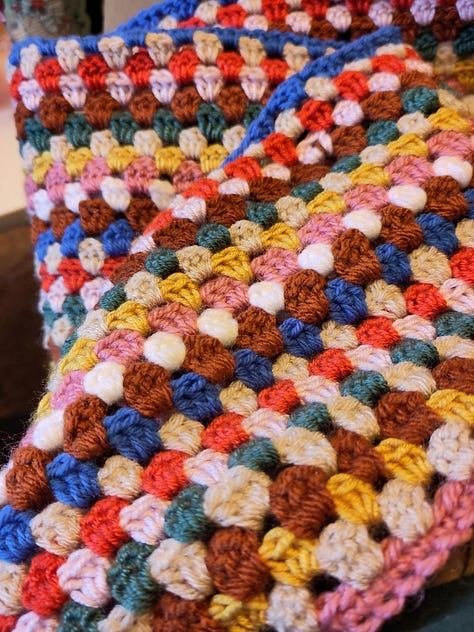 9 pictures of different fiber arts projects including a knit tapestry that says "Protect Trans Youth, a crochet tapestry of a wee ghost, a crochet blanket, a table runner, needle felted keychains, a butterfly cardigan for a little kid, and a blue and white striped cardigan for an adult.