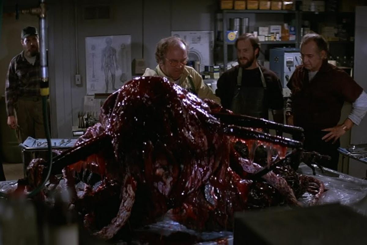 A grotesque, transforming creature mid-mutation with exposed organs and melting flesh — showcasing The Thing’s iconic practical effects and body horror.