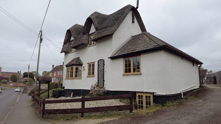 A thatched cottage painted white in the village of Rowde. The village hall was once the reading room.