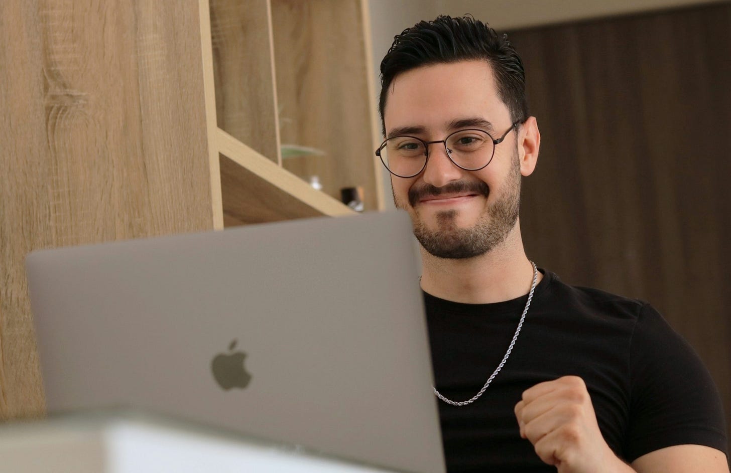 a man wearing glasses is looking at a laptop a man wearing glasses is looking at a laptop