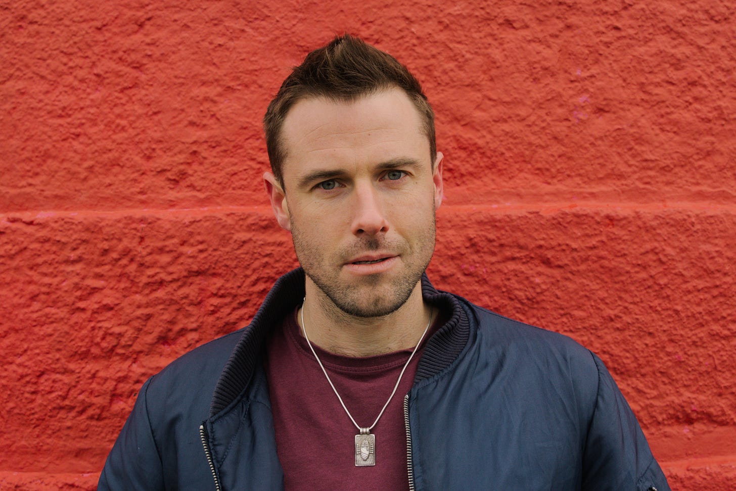 Oisín Fagan headshot against a bright red wall