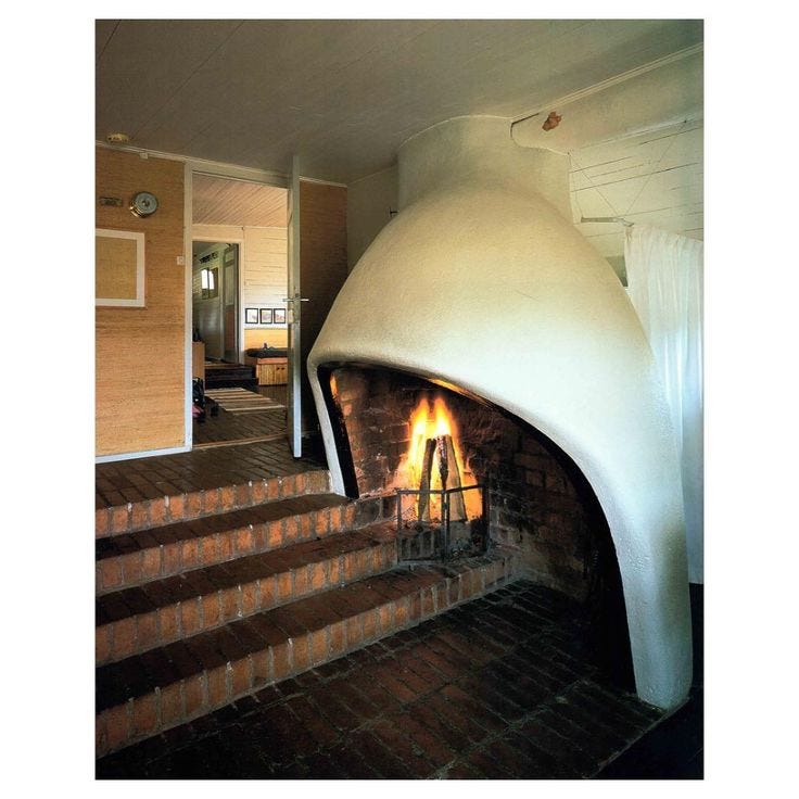 This may contain: a fire place in the middle of a living room with stairs leading up to it