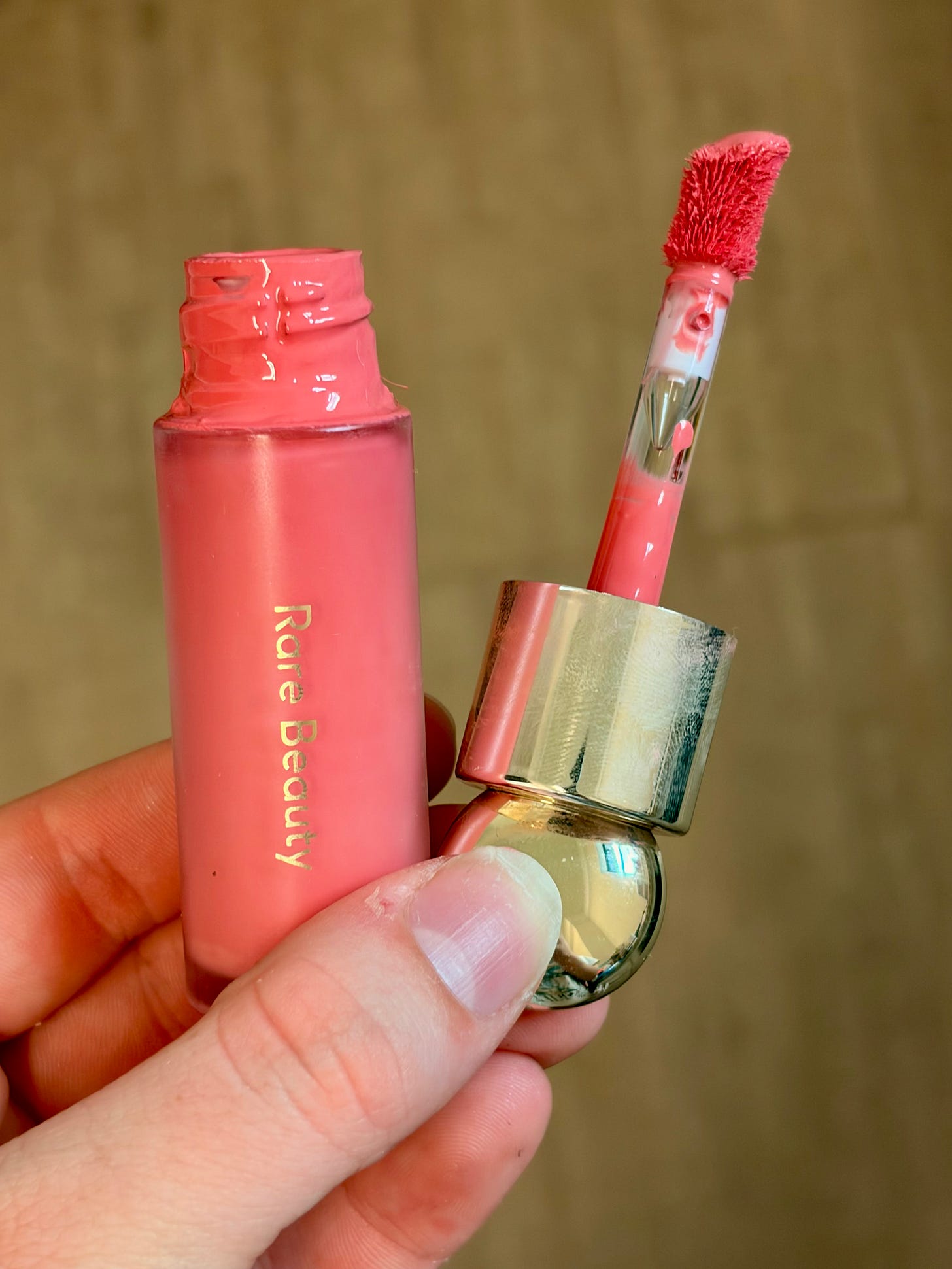 A dewy bottle of Rare Beauty Soft Pinch Liquid Blush sitting on a clean vanity countertop in bright daylight.