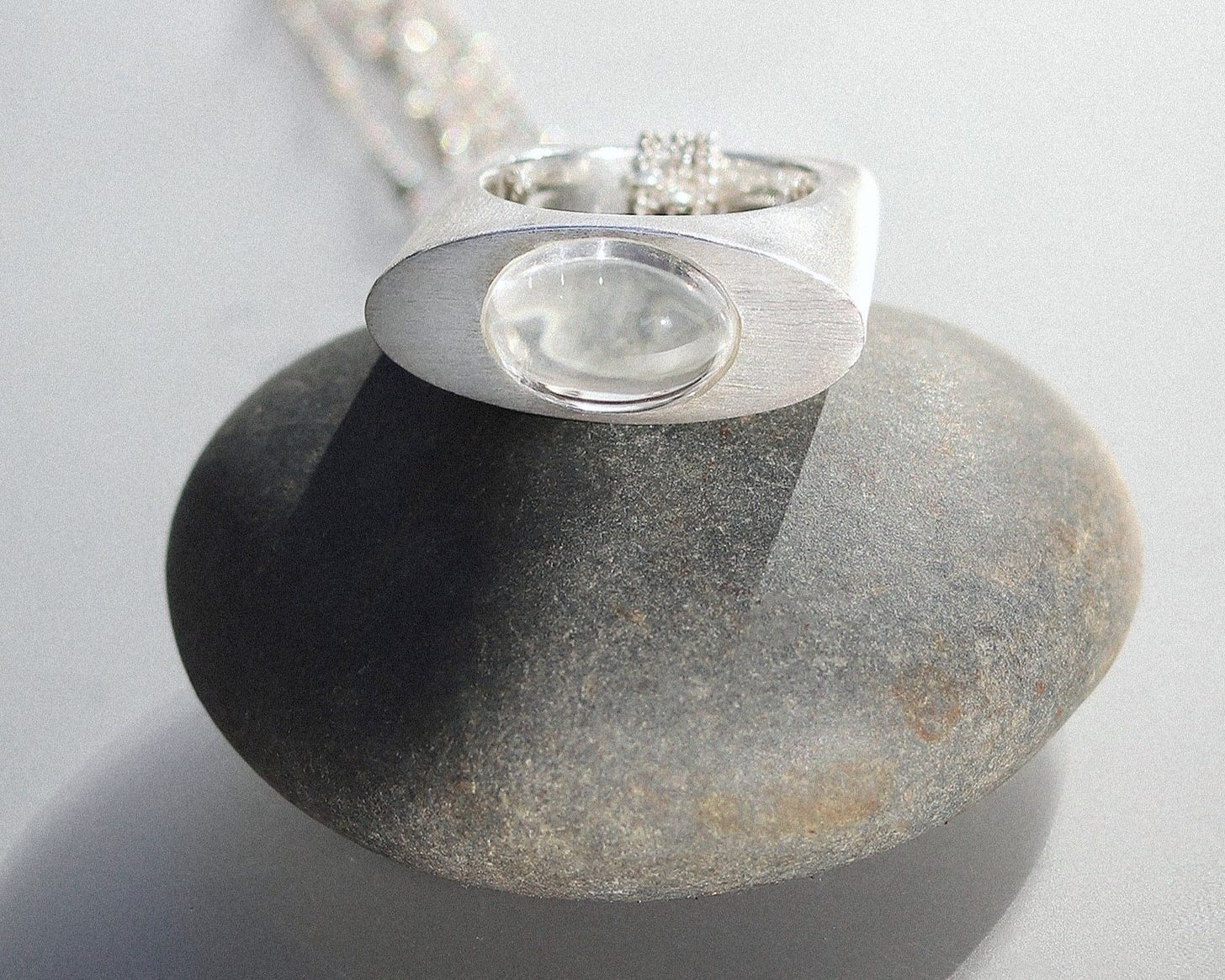 A Clear Quartz Silver Pendant Ring on a rock - ON IISLAND