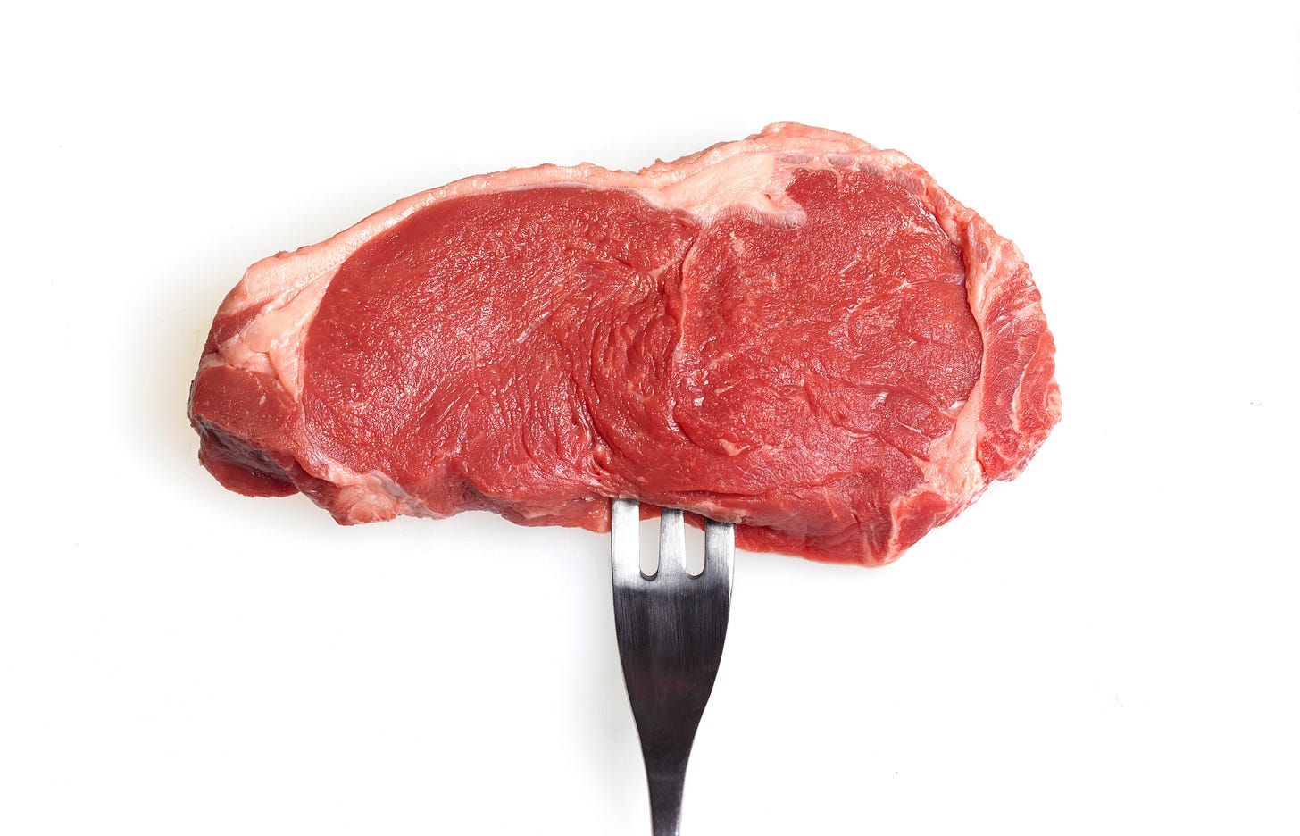 A fork stuck in a raw piece of meat