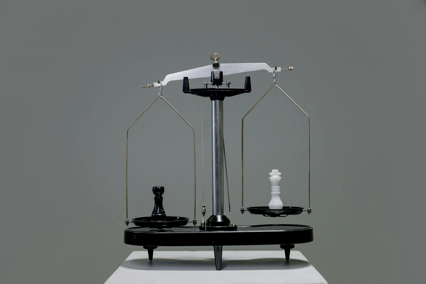 Two chess pieces on a scale, tipped to one side. Two chess pieces on a scale, tipped to one side.
