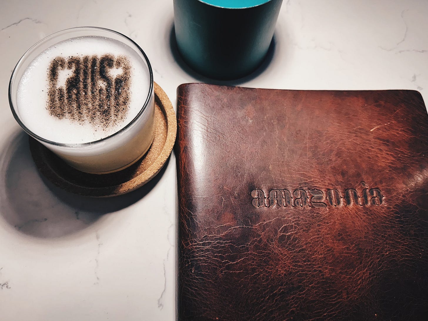 Leather-bound Amazonia menu beside a pisco sour on a marble table at Amazonia restaurant in Shaw, Washington DC Leather-bound Amazonia menu beside a pisco sour on a marble table at Amazonia restaurant in Shaw, Washington DC
