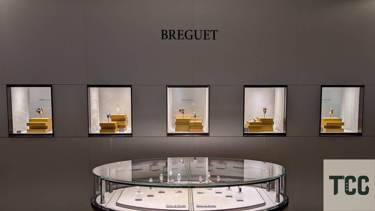 Wall-mounted display cases at Breguet featuring individual watches and a central round showcase labeled Reine de Naples with additional watches.