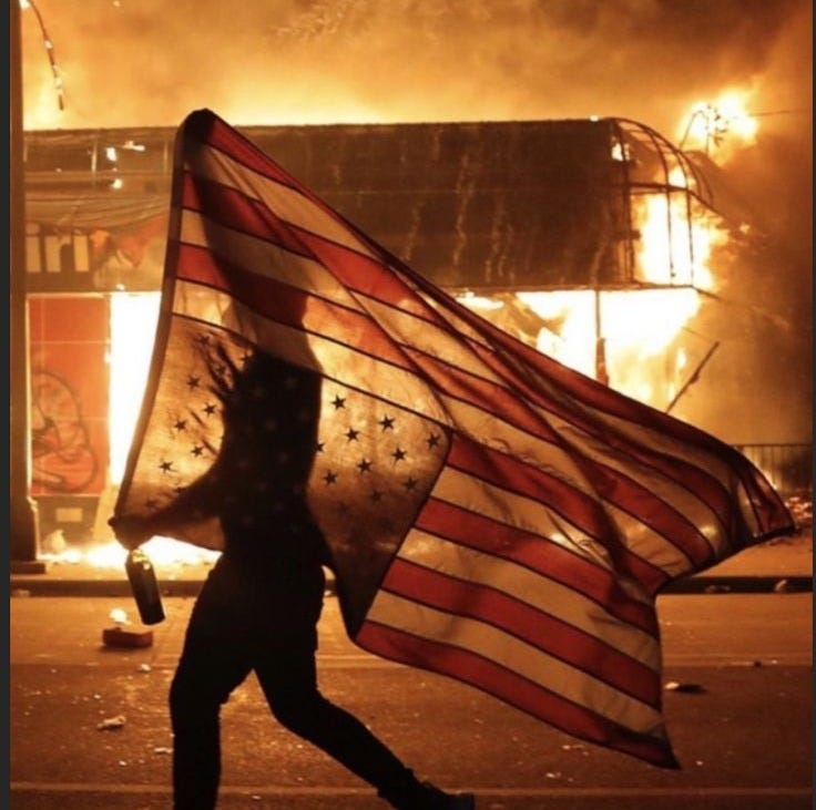 This may contain: a person holding an american flag in front of a fire