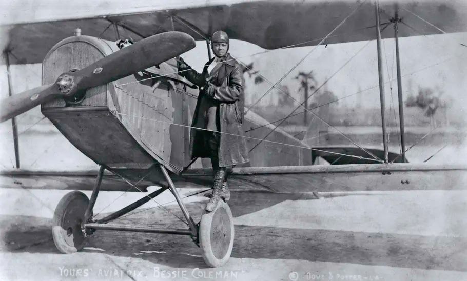 A black and white image of a young woman in flight gear standing on the wheel of her aircraft. A black and white image of a young woman in flight gear standing on the wheel of her aircraft.