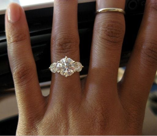 This may contain: a woman's hand with an engagement ring on it