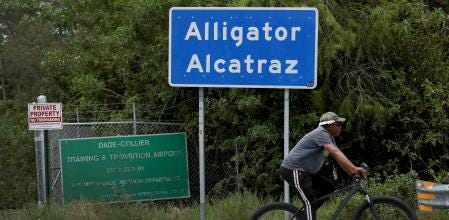 Un ciclista pasa junto al letrero de la entrada principal del centro de detención de inmigrantes en los Everglades de Florida 