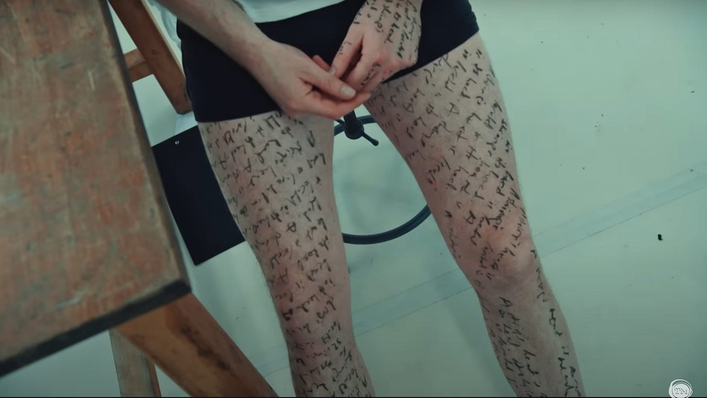 Little Alex Horne stands in his boxers, with indecipherable writing all over his legs.