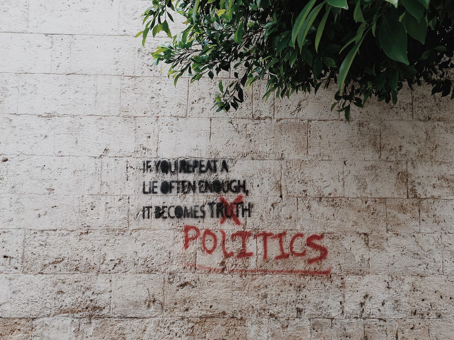 Grafitti on a wall in black paint reads "If you repeat a lie often enough it becomes truth." A red X is marked over the word "truth" and below it is written "politics." Grafitti on a wall in black paint reads "If you repeat a lie often enough it becomes truth." A red X is marked over the word "truth" and below it is written "politics."