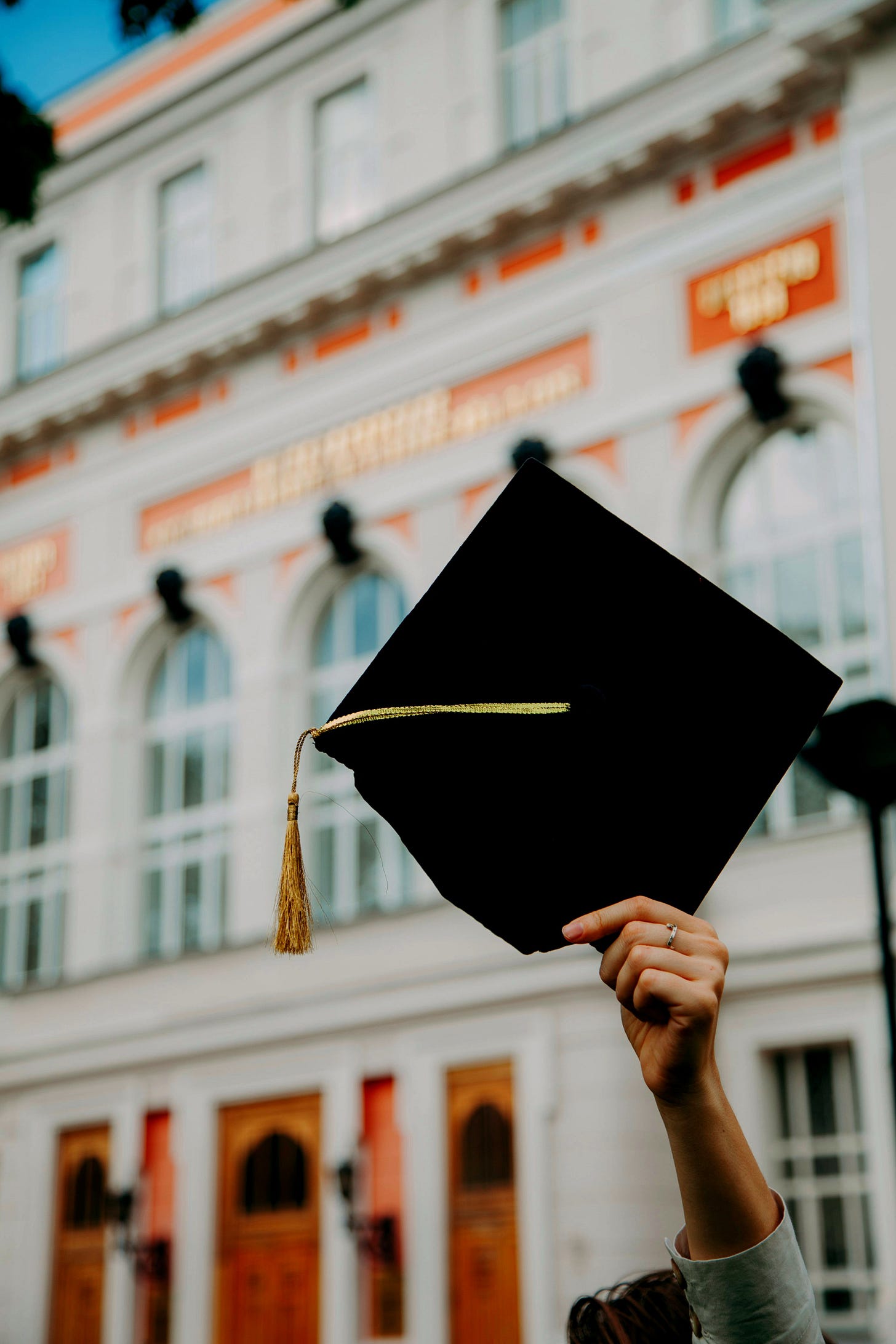 person holding black academic hat person holding black academic hat
