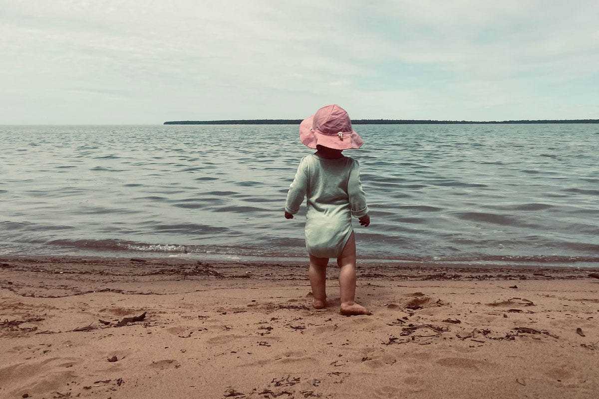 Baby standing on beach looking at Lake Superior