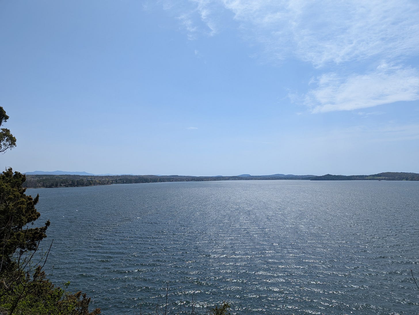 a view of Lake Champlain on a blue sky day with a view of the adirondack mountains int he distance