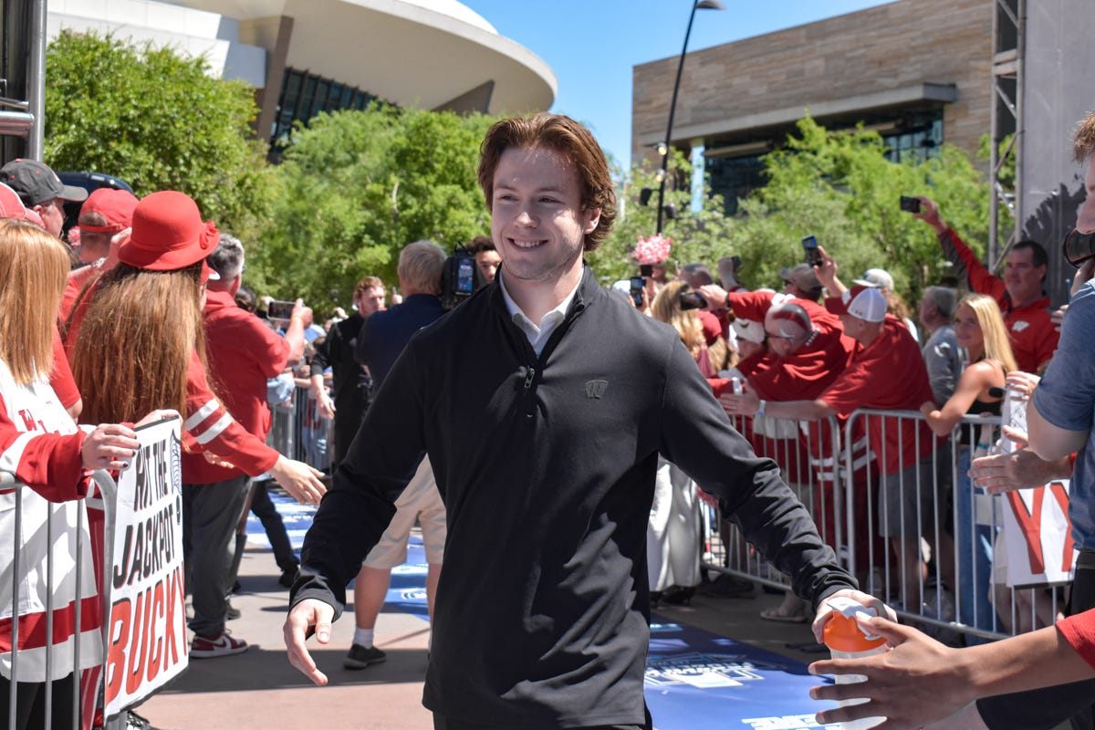 Daniel Hauer smiling while holding a water bottle as he walks in